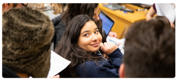 Student in psychology class looks over shoulder at classmates and smiles